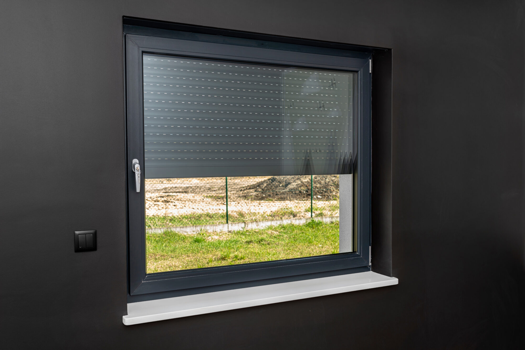 a large window in a room with black walls, half covered with external blinds